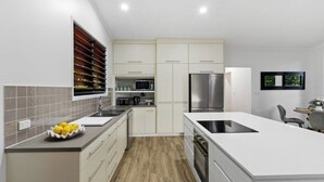 Eine moderne Küche mit weißen Schränken, einem Edelstahl-Kühlschrank und einem eingebauten Backofen.
