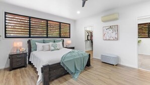 Ein Schlafzimmer mit einem Bett, Nachttischen, einem Deckenventilator, einem Kleiderschrank und einer kleinen Bank.