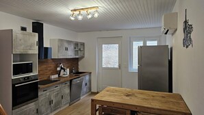 Une cuisine compacte équipée d’un four à micro-ondes, d’un four traditionnel, d’un lave-vaisselle et d’une table en bois.