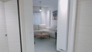 Een moderne, minimalistische woonkamer met een bank, een salontafel en een hanglamp.