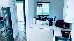 Eine moderne Küche mit Edelstahlkühlschrank, einer Spüle und einem Essbereich mit Fenster.