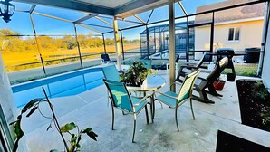 Eine moderne Terrassenanlage im Freien mit Glasveranda, Pool und Tisch mit Stühlen.