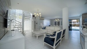 A modern living room with a white sofa, a coffee table, and a TV mounted on the wall.