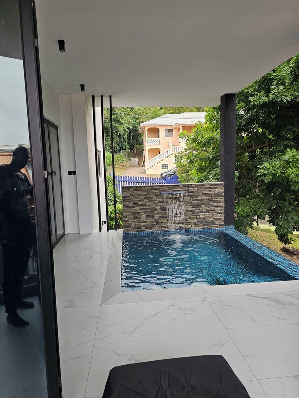 A modern indoor swimming pool with a stone wall and a blue fence.