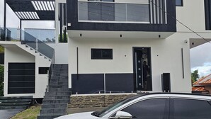 A modern two-story house with a white exterior and dark accents, featuring a prominent staircase and a garage.