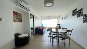 A modern living space with a dining area, a sofa, and a decorative wall piece. - Oceánica Luxury Apartment (Salinas)