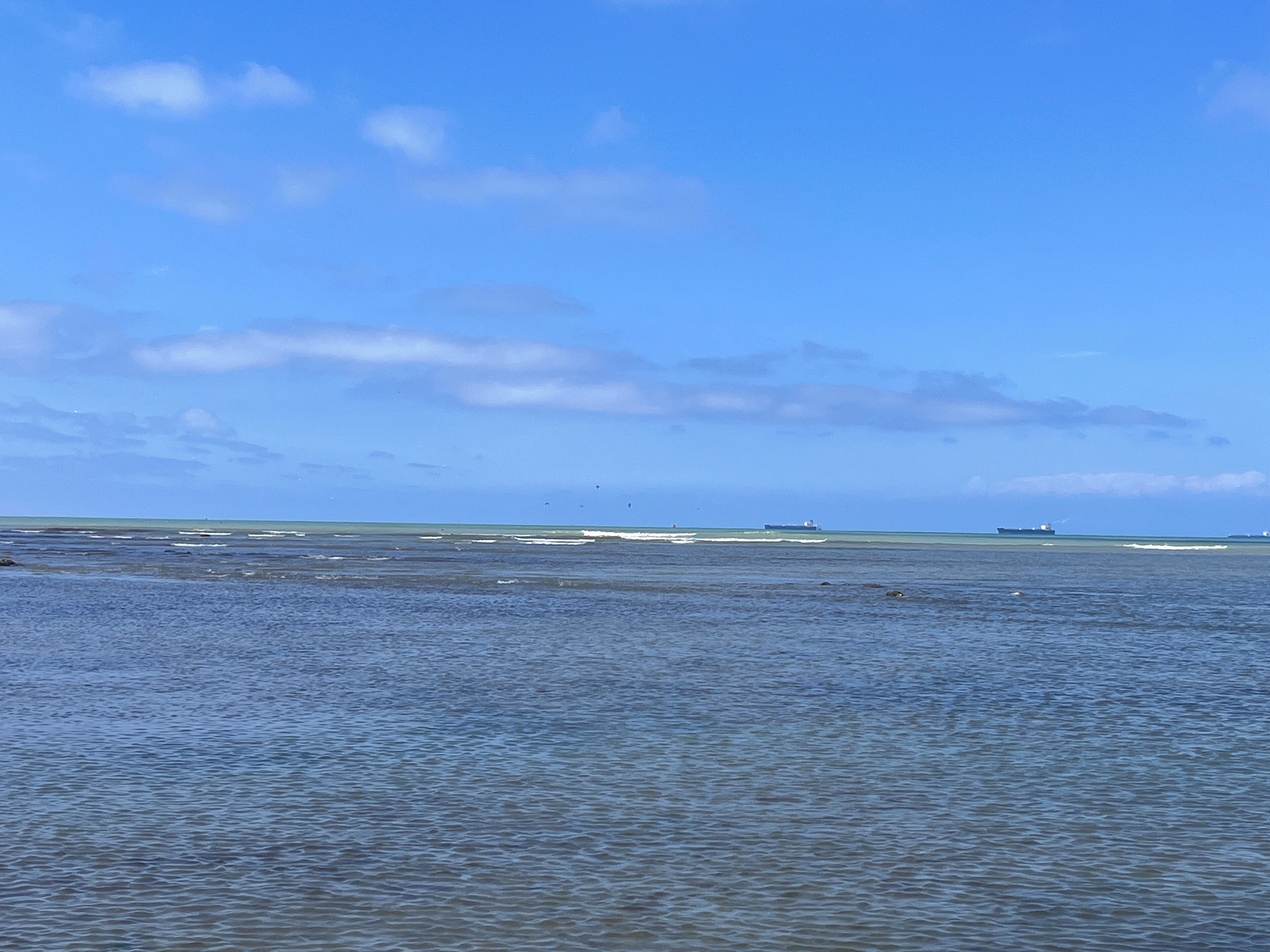 A coastal landscape with calm waters and a clear sky.