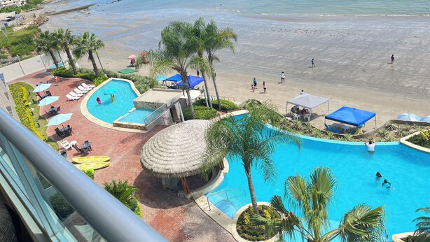 A resort with a swimming pool, beach, and city skyline. - Oceánica Luxury Apartment (Salinas)