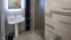 A modern bathroom with a white sink, a mirror with blue lighting, a glass shower enclosure, and a tiled floor. - Elegance and relaxation in an exclusive ground floor apartment flooded with light. (Carpegna)