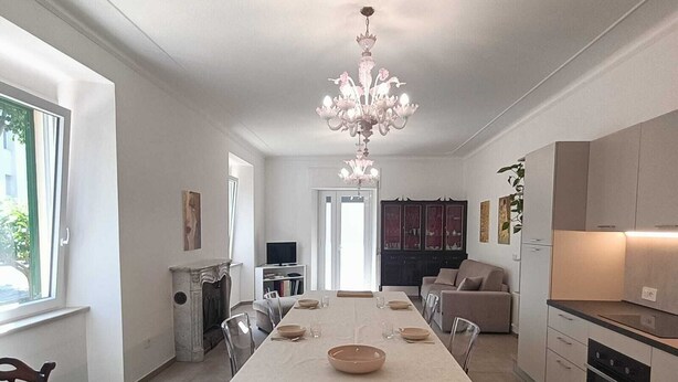 A modern kitchen with a central island, a dining area with a long table, and a chandelier. - Elegance and relaxation in an exclusive ground floor apartment flooded with light. (Carpegna)
