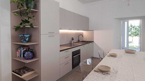 A modern kitchen with white cabinetry, a built-in oven, and a dining area with a table set for two. - Elegance and relaxation in an exclusive ground floor apartment flooded with light. (Carpegna)