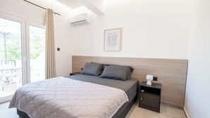Un dormitorio con cama, mesita de noche, una obra de arte enmarcada y un ventanal corredero que da a un espacio exterior.