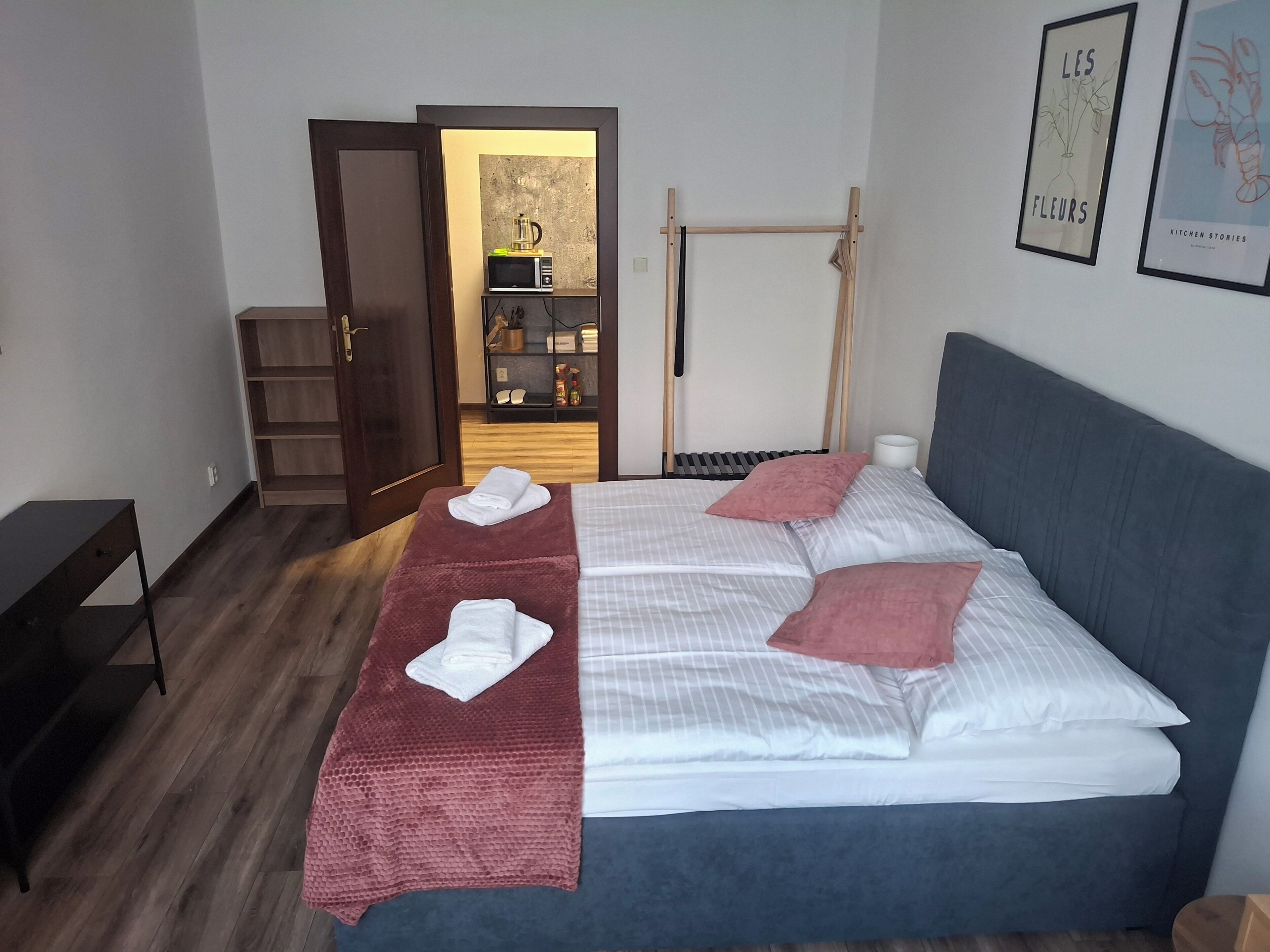 Ein Hotelzimmer mit einem Bett, einer Holzbank, einem kleinen Tisch, einem Kleiderschrank und einer Tür zu einem Badezimmer.