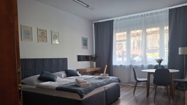 A hotel room with a bed, a desk, a chair, and a window with curtains. - „Stylish Apartment  • 2 min Metro Anděl  -4 guests (Prague)