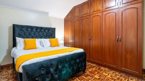 Ein Schlafzimmer mit einem großen Bett, einem Holfischschrank und einem Parkettboden mit Zickzackmuster.