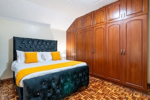 Ein Schlafzimmer mit einem großen Bett, einem Holfischschrank und einem Parkettboden mit Zickzackmuster.