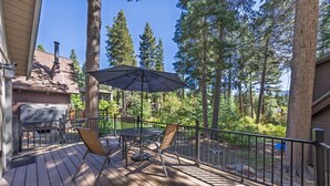 Une terrasse en bois avec une table et des chaises, un parasol et un barbecue.