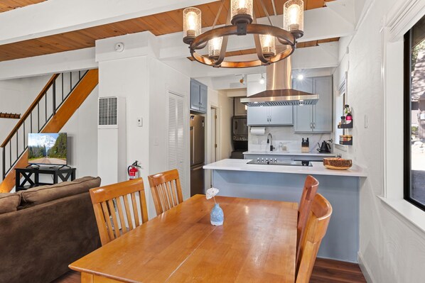 A modern kitchen with a central island, stainless steel appliances, and a wooden dining table with chairs.
