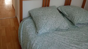 A bedroom with a wooden headboard, a bed with patterned bedding, and a wooden floor. - Lille Centre Lille Europe station (Lille)