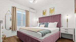 Un dormitorio moderno con una cama grande, una mesita de noche, un espejo y una ventana con cortinas.