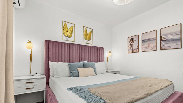 A neatly arranged bedroom with a large bed, two bedside tables, and wall art. - Unique 2-Home Family Getaway Near Beaches Airport Restaurants.  Ideal for Groups (Arenales)