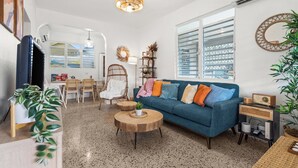 A living room with a blue sofa, round wooden coffee table, and a television on a stand. - Unique 2-Home Family Getaway Near Beaches Airport Restaurants.  Ideal for Groups (Arenales)