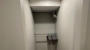 Un couloir étroit doté d’un plancher en bois, de murs blancs et d’un luminaire au plafond.