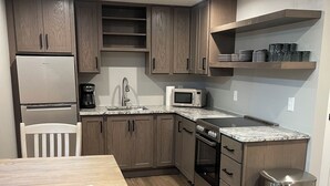 Une cuisine moderne avec des meubles en bois, un réfrigérateur en acier inoxydable, un four à micro-ondes et une machine à café.