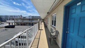 Ein Balkon mit einer blauen Tür, einem Stuhl und Blick auf einen Parkplatz sowie Gebäude.