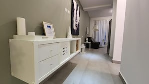 Ein modernes Wohnzimmer mit einem weißen Konsolentisch, einem gerahmten Zertifikat und einer Schwarz-Weiß-Kunstausstellung an der Wand.