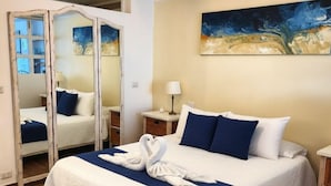 Ein Hotelzimmer mit einem großen Bett, einem Spiegel, einem Bild an der Wand und Holzboden.
