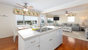 A compact kitchen with a central island, white cabinetry, and a ceiling fan. - Sea Salt and Sunshine: Family & Pet Friendly (Surf City)