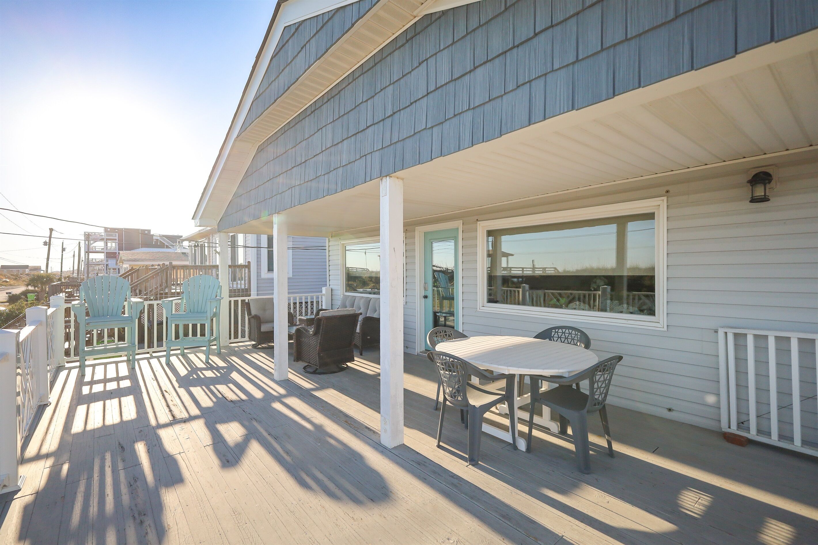 A covered porch with outdoor seating and a view of the ocean.