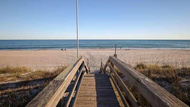 A wooden boardwalk leading to a sandy beach with a clear sky. - Sea Salt and Sunshine: Family & Pet Friendly (Surf City)
