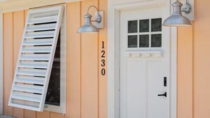 A house with a white door, a window with shutters, and a number '1230' on the wall. - Ocean Isle Retreat (Ocean Isle Beach)