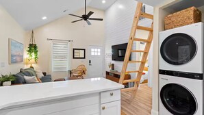 A modern kitchen with a central island, built-in appliances, and a wooden ladder. - Ocean Isle Retreat (Ocean Isle Beach)