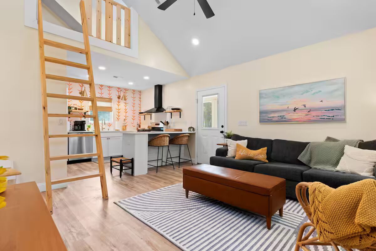 Un grand espace de vie comprenant un salon avec une chambre en mezzanine, une cuisine et un coin repas.