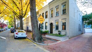Una calle con coches estacionados, un cartel de reductor de velocidad y un edificio con fachada de ladrillo.