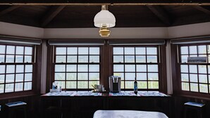 A room with large windows, a table with a coffee maker, a bottle, and a lamp. - The Folly PLUS, University Place View Home with Pool, Perfect  for Celebrations. (University Place)