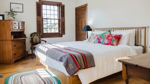 A bedroom with a wooden bed, a nightstand, a dresser, a window with shutters, and a rug. - The Folly PLUS, University Place View Home with Pool, Perfect  for Celebrations. (University Place)