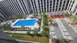 Un bâtiment moderne doté d’une piscine sur le toit, de chaises longues et d’un espace salon abrité.