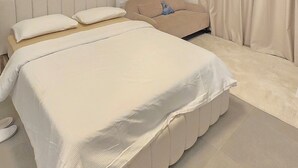 Une chambre à coucher avec un grand lit, une tête de lit, une table de chevet et une fenêtre avec des rideaux.