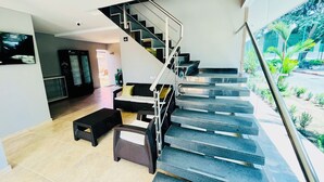 A modern interior with a staircase, a sofa, and a television. - Hotel Payara (Puerto Gaitán)