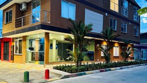 A multi-story building with a ground-level commercial space, large windows, and a balcony. - Hotel Payara (Puerto Gaitán)