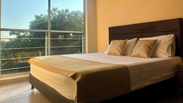 A hotel room with a large window, a bed with a wooden headboard, and an air conditioning unit on the wall. - Hotel Payara (Puerto Gaitán)