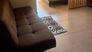 A modern bedroom with a large bed, a sofa, and a view of greenery outside. - Hotel Payara (Puerto Gaitán)
