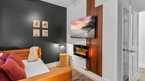 Quarto moderno com cama, TV fixada na parede e lareira.