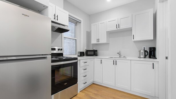 A modern kitchen with white cabinets, a stainless steel refrigerator, a microwave, and a stove. - Amazing location in the heart of Gatineau.#5 (Gatineau)