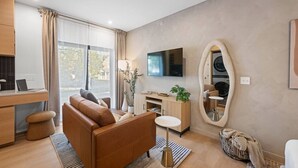 Un soggiorno moderno con un divano, una TV e un grande specchio.