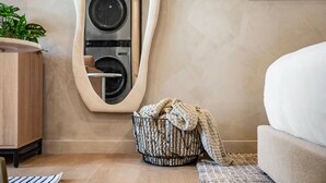 Un bagno moderno con uno specchio grande, una lavatrice, un armadietto in legno e un angolo relax con una coperta.